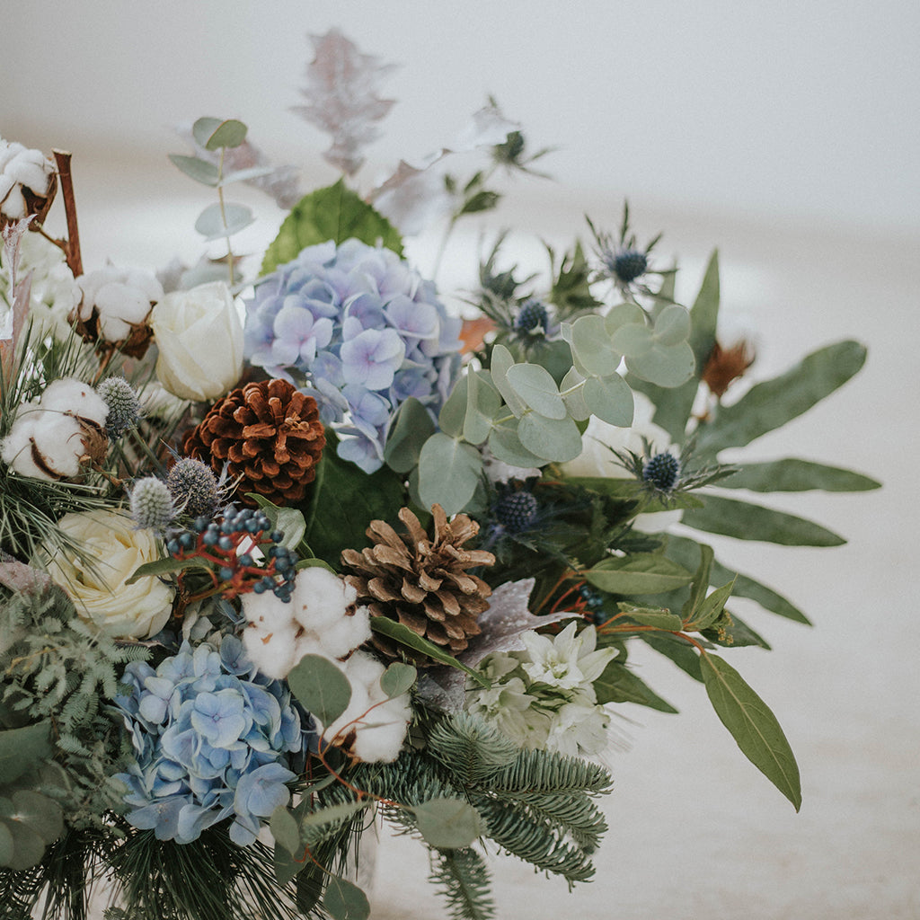 Base de cerámica con flores invernales en tonos fríos